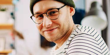 A content and relaxed man smiling on a couch at home; illustrating the long-term benefits of authoritative parenting and the foundational life principles that shape a well-adjusted adulthood.
