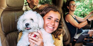 A mother and her young children enjoying a car trip together with their family dog; illustrating a 'secure attachment lifestyle' and the supportive environment where traditional, loving affirmations are passed down.