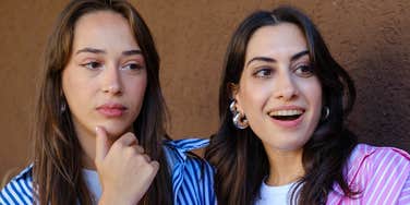 One woman bragging while the other looks annoyed in conversation 