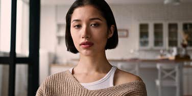 Young woman who can't get her life together standing sadly in the kitchen