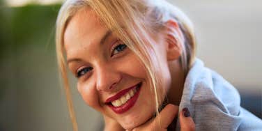 A confident young woman smiling warmly in a bright, modern setting; a visual representation of 'the unhurried communicator' who effortlessly commands a room when speaking.