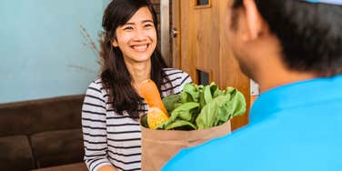 happy woman receiving grocery delivery instead of going shopping herself