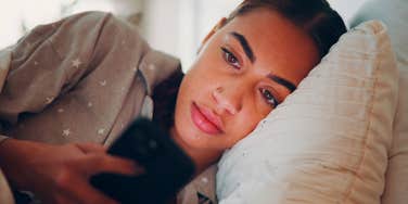 woman checking social media at the end of the day in bed