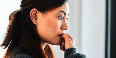 anxious woman biting her nails overthinking and analyzing