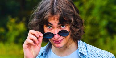 man with bad character smirking lowering his sunglasses