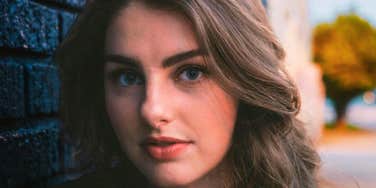 A close-up portrait of an attractive woman walking outdoors on a blurred background; illustrating 'the familiarity trap' and how casual, everyday proximity can impact marital boundaries.