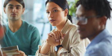woman surrounded by colleagues and staying silent during important work meeting