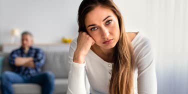annoyed woman expecting her husband in background to make sacrifices for her