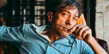 man holding glasses being rude but trying to act nice