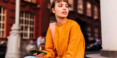 young woman looking unhappy while holding her phone