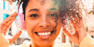 gen z woman smiling listening to music on headphones