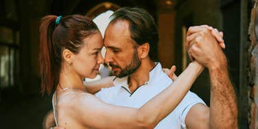 A passionate couple dancing the tango together on a city sidewalk; a visual representation of 'the unplugged courtship' that characterized the analog romance of the Gen X generation.