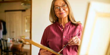 happy woman painting a canvas as a hobby