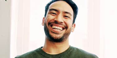 A close-up portrait of a happy, man smiling and laughing while; illustrating natural, unforced positive body language and digital attraction.