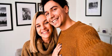 happy millennial couple hugging and taking a photo