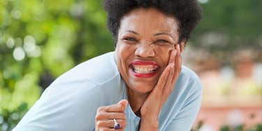 Medium shot of a cheerful Black woman in her late forties smiling during an outdoor leisure activity; illustrating 'the intermittent longevity framework' where career breaks happen during peak physical health.