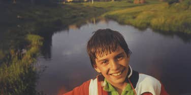 Boy in the 1980s having fun posing by a river