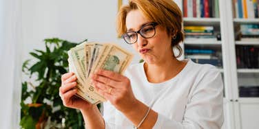 young woman not abiding by money rules while holding cash