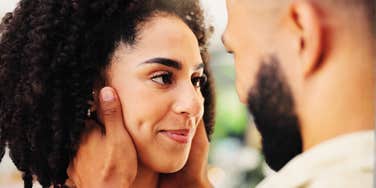A warm, cinematic portrait of a man embracing his partner's face with tender affection, capturing quiet self-assurance and unreserved devotion.