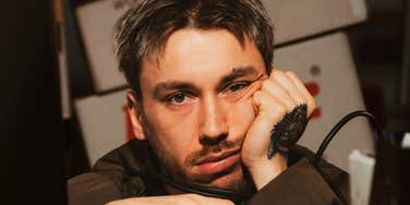 A portrait of a man resting his chin on his hand with a somber expression, illustrating passive resignation, low self-efficacy, and chronic self-pity.