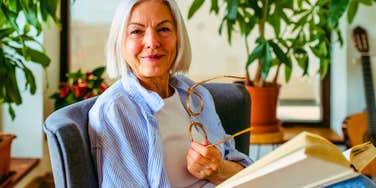older woman raised before the internet reading a book smiling