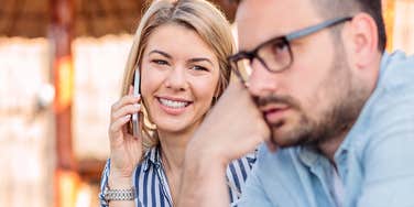 Emotionally high-maintenance woman smiling while her husband is annoyed