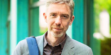 An outdoor portrait of a confident 50-year-old man with a beard; a visual representation of 'the effortless practitioner' who masters daily execution with calm authority.