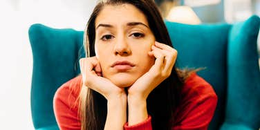 Indoor portrait of an anxious young woman curled up on a sofa looking unbothered by accountability and integrity.
