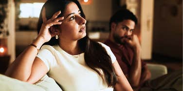 sad wife feeling lonely at home while husband sits next to her