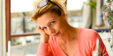 A woman sits thoughtfully at a restaurant table; a visual representation of 'the introspective break' used to explore lingering therapeutic breakthroughs.