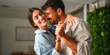 husband who feels appreciated dancing happily with wife at home