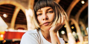 A close-up portrait of an attractive European woman with short hair looking directly into the camera with an intense, discerning expression.