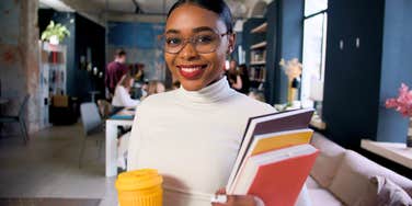millennial woman smiling in the workplace holding her work
