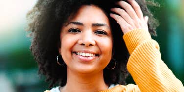 A cheerful young woman laughing outdoors on a sunny day, symbolizing emotional freedom, inner peace, and healthy mental boundaries.