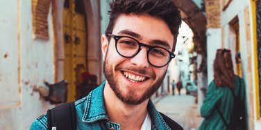 A man wearing glasses gesturing naturally during a casual conversation outdoors, symbolizing high social intelligence, rapport-building, and communication ease.
