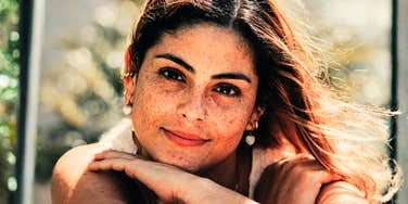 A woman looking at the camera with a calm, confident smile outdoors, symbolizing emotional self-regulation, personal boundaries, and grounded communication.
