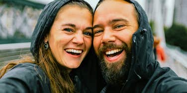 A happy adult couple laughing and talking affectionately together in a relaxed outdoor environment.