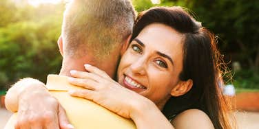 A happy couple hugging outdoors in warm golden hour sunlight, symbolizing emotional security, romantic fulfillment, and healthy dating habits.