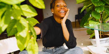 smiling woman happy spending time alone sitting with her plants