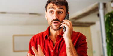 A man making an animated hand gesture while talking on a phone, symbolizing emotional dysregulation, conflict resistance, and lack of accountability.