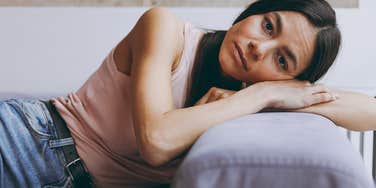Gen Z woman with bad habits that are a problem looking sad on a couch 