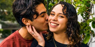 happy gen Z coupld smiling with man kissing woman's cheek