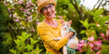 baby boomer woman holding cat while gardening as a hobby
