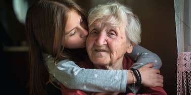 Baby boomer grandmother being hugged by her Gen Z granddaughter 