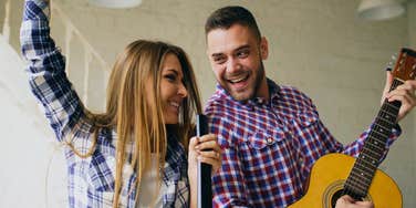 happy couple singing and dancing together playing guitar