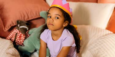 undisciplined little girl sitting in bed with a crown not listening