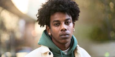 sensitive young man looking serious and self-aware outdoors 