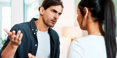 A man and woman engaging in a heated indoor confrontation, symbolizing communication breakdowns, relationship strain, and marital conflict.