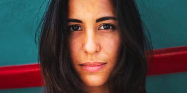 A powerful close-up photo of a young woman staring calmly and attentively, representing emotional resilience, grounded self-worth, and authentic empathy.
