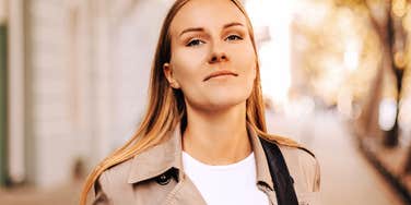 A professional woman smiling confidently in a modern setting, symbolizing emotional resilience, self-possession, and healthy interpersonal boundaries.